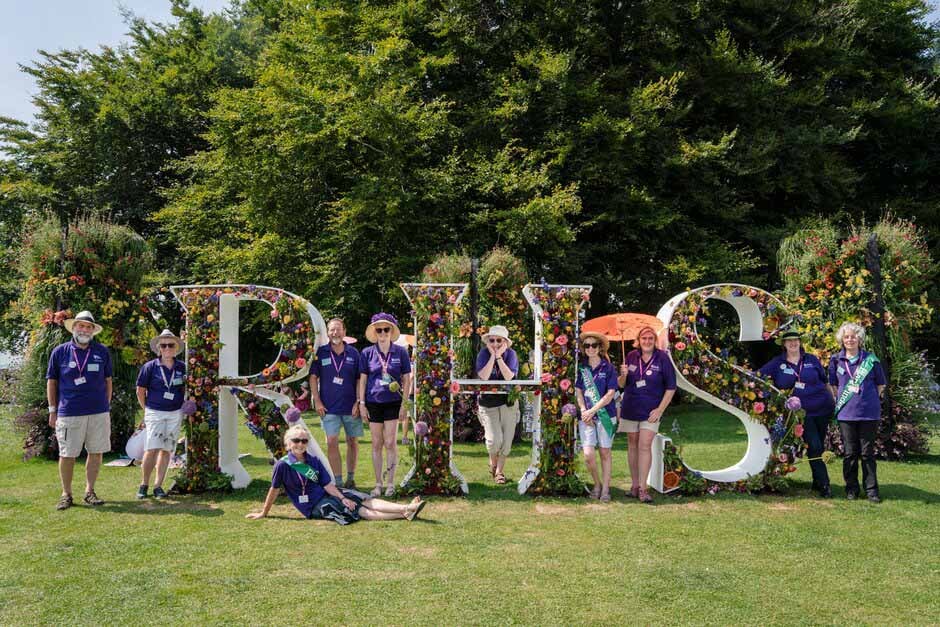 Show volunteers pose by the RHS Letters at RHS Tatton Park